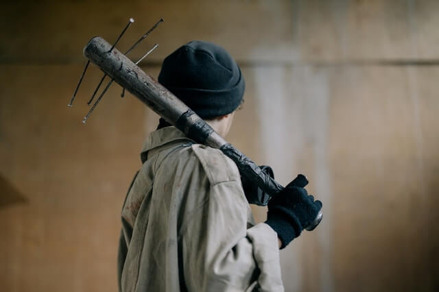 Un homme tenant une batte cloutée pour illustrer la fabrication d'arme maison
