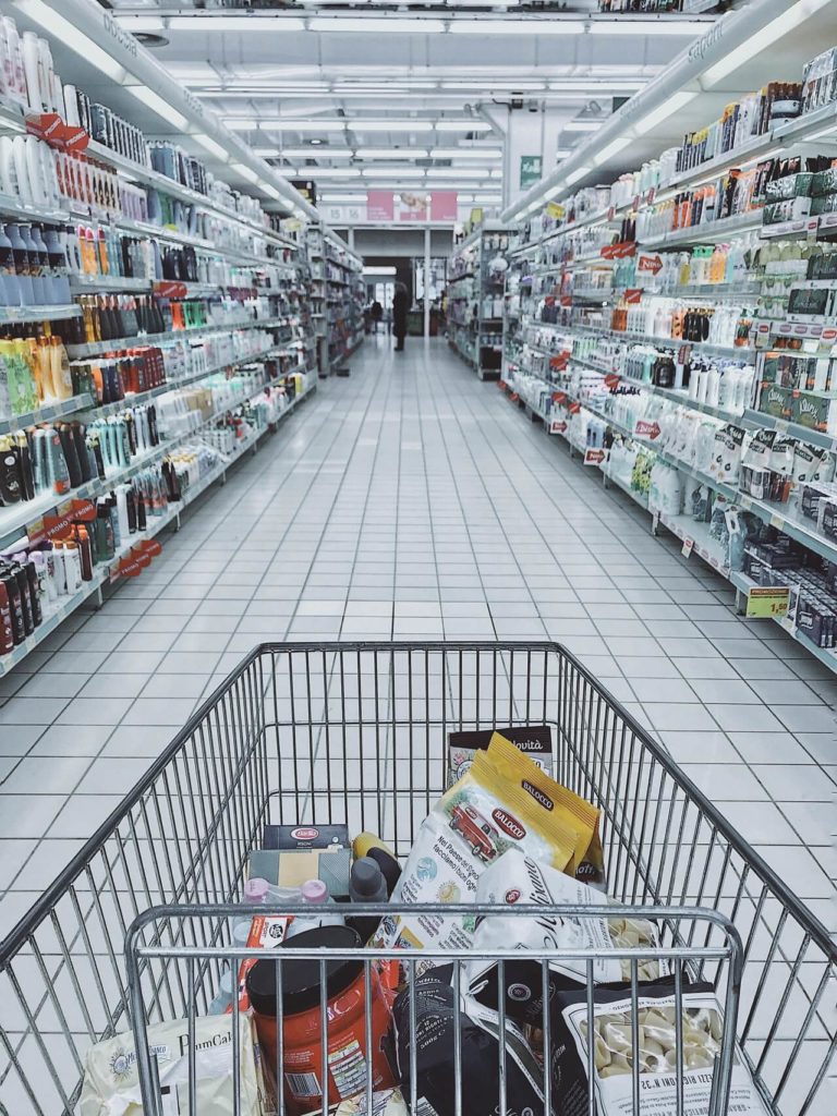 Photo d'un chariot dans un supermarché pour illustrer l'achat de produits indispensables pour un challenge un mois sans rien dépenser.