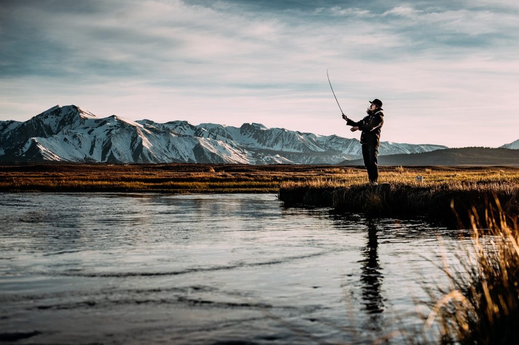 Un homme pêchant au bord d'un lac pour montrer les ressources naturelles qui peuvent se trouver à proximité de son environnement