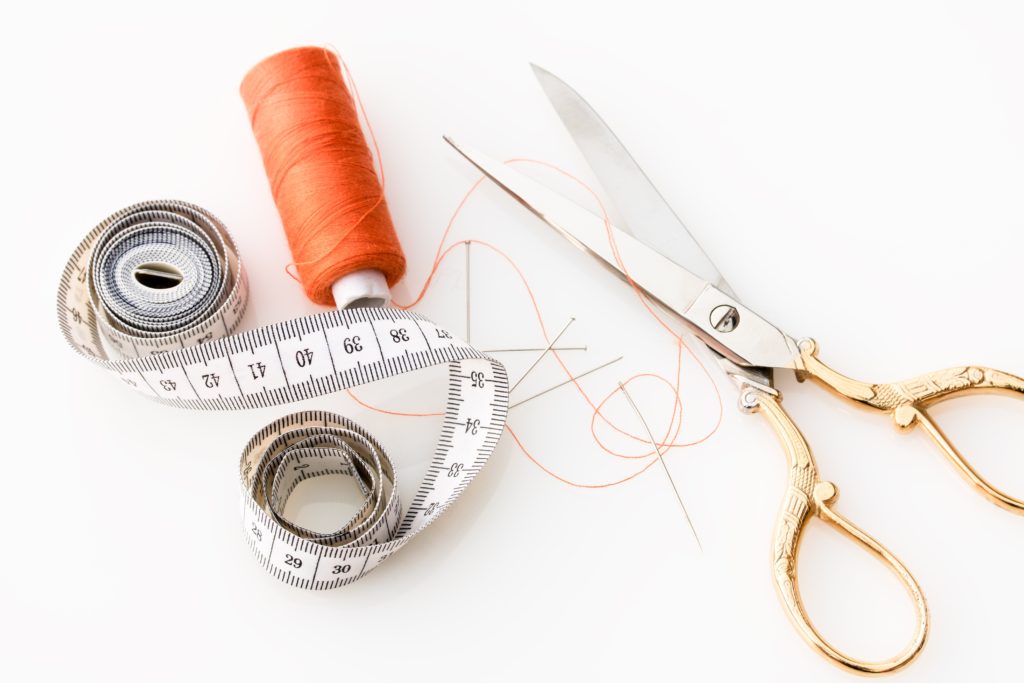 Set de couture contenant des ciseaux, un mètre ruban et du fil à coudre orange pour réparer ses affaires au lieu de les jeter et réduire ses déchets ménagers